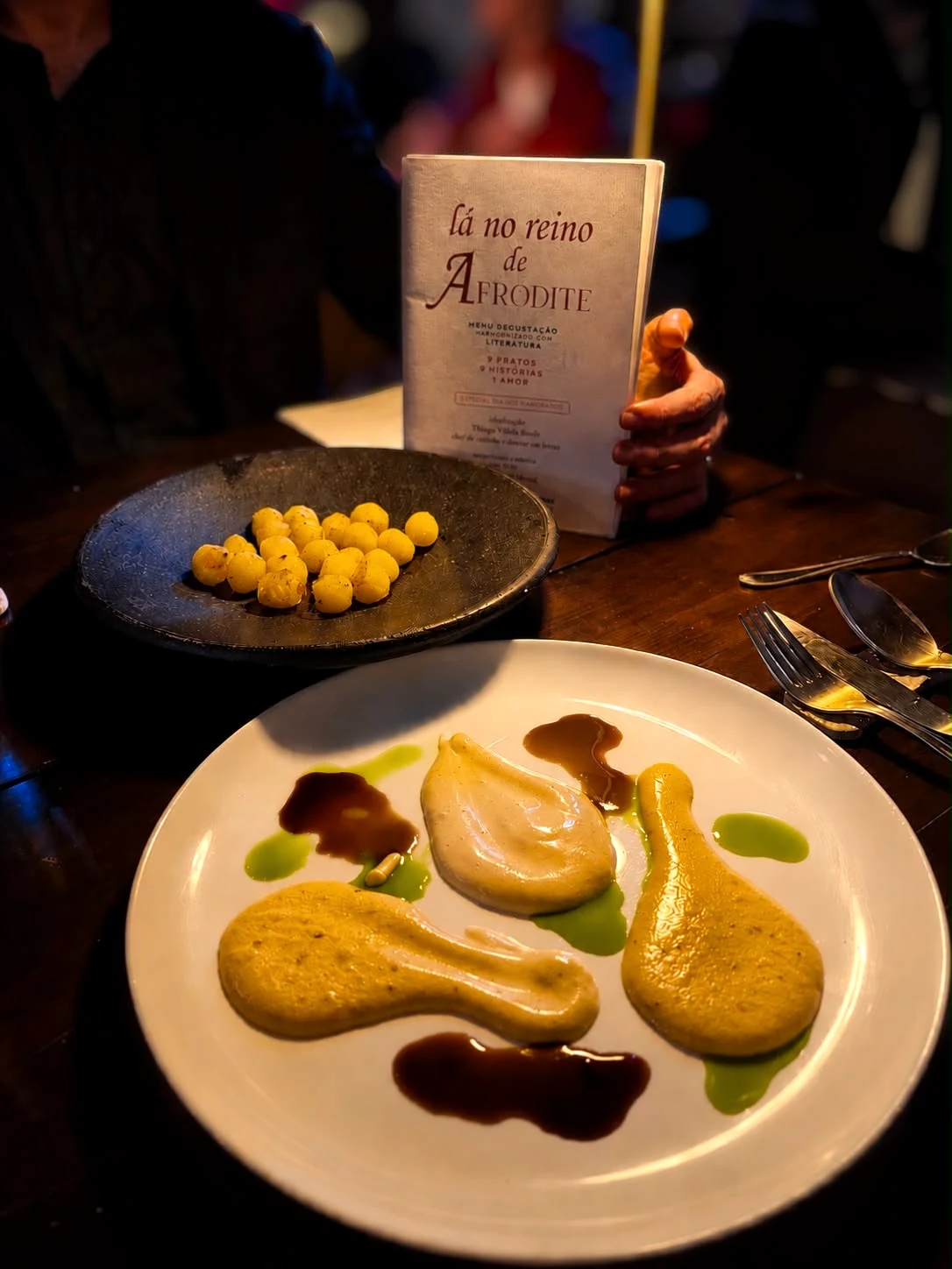 Pratos e livreto do menu Lá no Reino de Afrodite